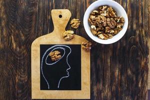 drawn person head with brain and nuts walnuts on wooden background. healthy food to think. photo