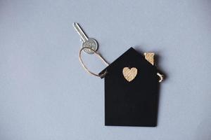 Little toy house with a key on a grey background. photo