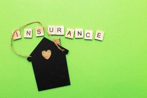 inscription insurance with a little house on a green background made by wooden blocks photo