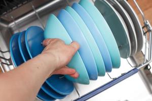 hand of a woman open dishwasher with clean dishes in the kitchen photo