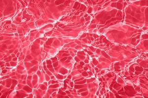 Defocus blurred transparent red colored clear calm water surface texture with splashes and bubbles. Trendy abstract nature background. Water waves in sunlight with copy space. Red watercolor shining photo