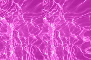 desenfoque borrosa textura de superficie de agua tranquila transparente de color púrpura con salpicaduras y burbujas. fondo de naturaleza abstracta de moda. ondas de agua a la luz del sol con espacio de copia. brillo de acuarela foto