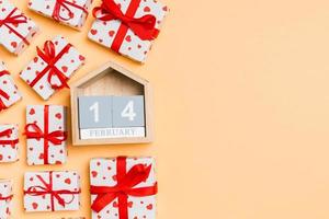 Holiday composition of gift boxes with red hearts and wooden calendar on colorful background with empty space for your design. The fourteenth of February. Top view of Valentine's Day concept photo