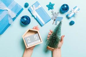 Top view of female hands holding calendar on blue background. The twenty fifth of December. Holiday decorations. Christmas time concept photo