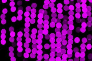 Unfocused abstract purple bokeh on black background. defocused and blurred many round light photo