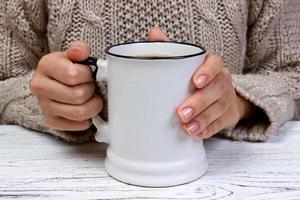 Woman's hands holding cup with coffee, top view photo