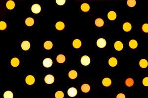 Unfocused abstract yellow bokeh on black background. defocused and blurred many round light photo