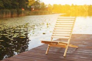 Wooden dock with lounge chair on pier on the calm lake in the middle of the forest photo