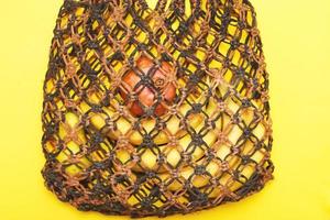 brown string bag with ripe fruits on a yellow background photo