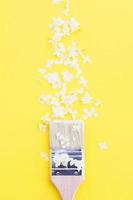 white hydrangea flowers and paint brush on a yellow background with copy space. photo