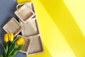 wood empty plates for snack and flowers on color grey and yellow background photo