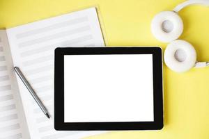 Top view open music book, headphones and a pen on a yellow background. mock up for music lessons photo