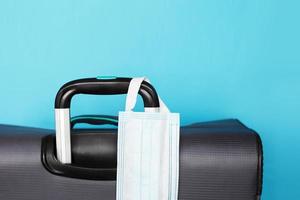 luggage bag and medical mask isolated on a blue background. protection Coronavirus disease infection. photo