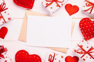 correo de sobre con corazón rojo y caja de regalo sobre fondo blanco de madera. tarjeta de san valentín, amor o concepto de saludo de boda foto