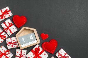 vista superior de cajas de regalo, calendario de madera y corazones textiles rojos sobre fondo colorido. catorce de febrero. concepto del día de san valentín con espacio de copia foto
