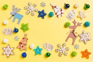 Top view of yellow background with New Year toys and decorations. Christmas time concept with copy space photo