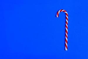 bastón de caramelo de navidad sobre fondo azul. endecha plana y vista superior. copie el espacio foto