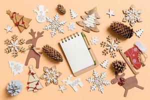 Top view of notebook surrounded with New Year toys and decorations on orange background. Christmas time concept photo