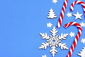 bastón de caramelo de navidad mintió uniformemente en fila sobre fondo azul con copo de nieve decorativo y estrella. plano y vista superior foto