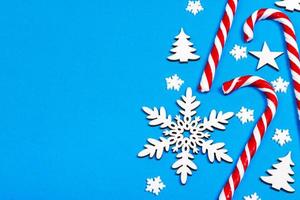 Christmas candy cane lied evenly in row on blue background with decorative snowflake and star. Flat lay and top view photo