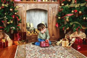 niño niño sentado bajo el árbol de navidad con caja de regalo foto