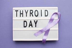 inscripción día internacional de la tiroides y cinta violeta sobre fondo púrpura foto