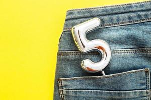 number 5 sticking out of the back pocket of blue jeans on yellow background photo