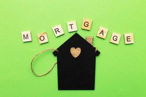 inscription mortgage with a little house on a green background made by wooden blocks photo