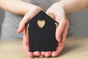 womans hand holding little toy house. Home insurance concept photo