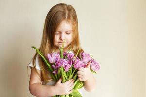 portrait of litlle girl with bouquet of flowers tulips in her hands photo