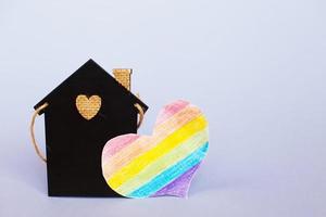 corazón en forma de bandera lgbt junto a una casa de juguete en miniatura. foto