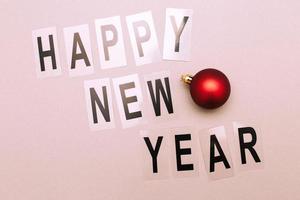 The inscription happy new year with shiny Christmas toy balls on a pink background photo