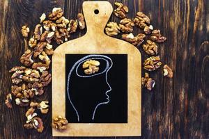 drawn person head with brain and nuts walnuts on wooden background. healthy food to think. photo