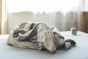 crumpled empty bed in a room on a window background. Weekend morning. messy blanket in bedroom after waking up photo