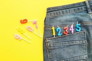 birthday candles sticking out of the back pocket of blue jeans on yellow background Number 0-9 photo