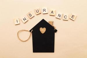 inscription insurance with a little house on a biege background made by wooden blocks photo