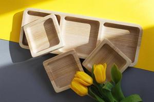 wood empty plates for snack and flowers on color grey and yellow background photo