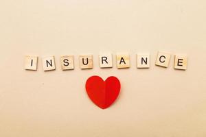 inscription insurance on a beige background made by wooden blocks with red heart photo