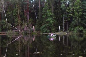 padre e hijo pescando en un lago rural al atardecer en un barco foto
