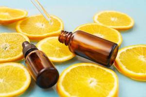 brown glass bottle with a pipette serum with vitamin C. Essential oil and orange slices. Health and beauty concept. photo