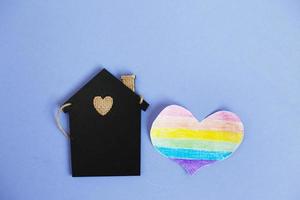 corazón en forma de bandera lgbt junto a una casa de juguete en miniatura. foto