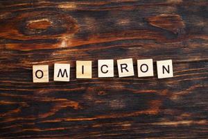 word omicron made by wooden blocks on wooden background. photo