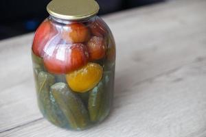 spoiled can of vegetable seaming. Glass jar with homemade pickled tomatos and cucumbers with white fungus photo