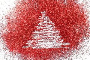 árbol de navidad dibujado con los dedos sobre fondo de confeti rojo brillante foto