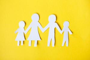 Happy paper cut family holding hands on yellow background photo