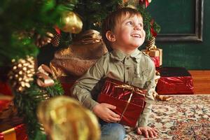 child boy sitting under the Christmas tree with gift box photo