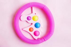 hoyuelo simple en forma de unicornio y un juguete de fidget de tubo sobre un fondo rosa foto