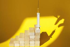 shadow of a man's hand about to steal a syringe with a vaccine on yellow background photo