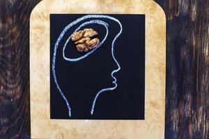 silhouette of person drawn head with abstraction brain in the form of walnut on black background. healthy food to think. photo