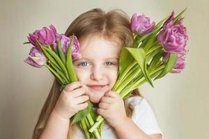 retrato de niña pequeña con ramo de flores tulipanes en sus manos foto